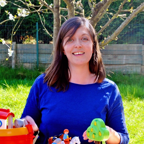 Femme assise qui sourit avec des jouets pour enfant devant elle