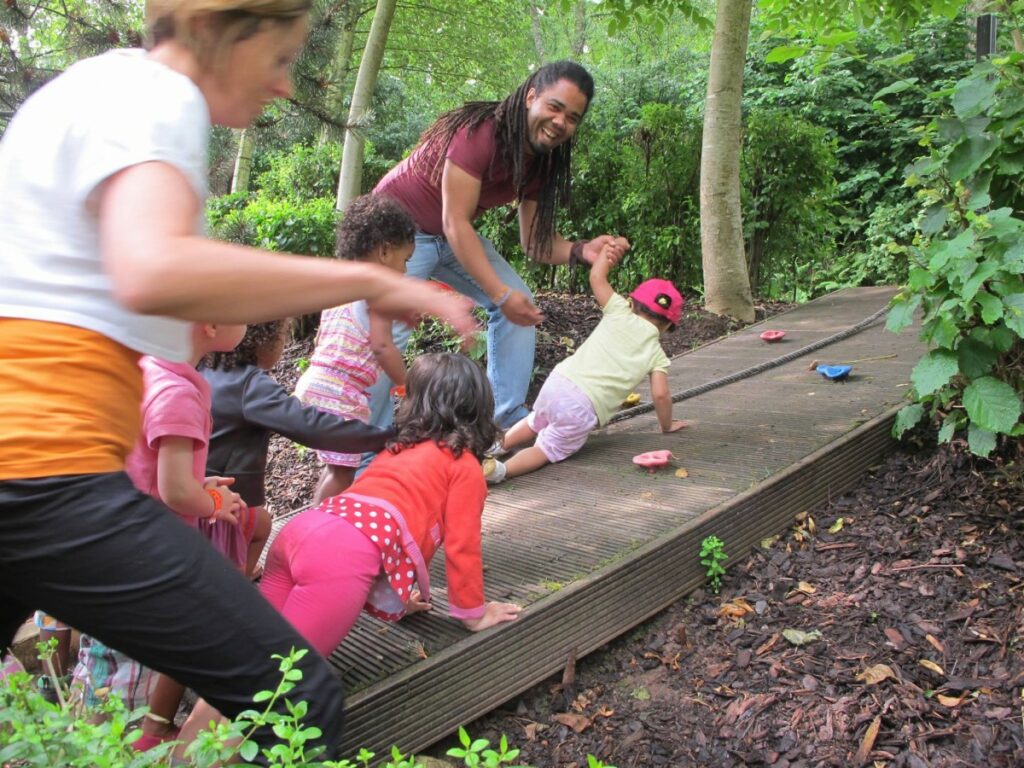 Cinq enfants accompagnés de deux éducateurs faisant de l'escalade dans les bois
