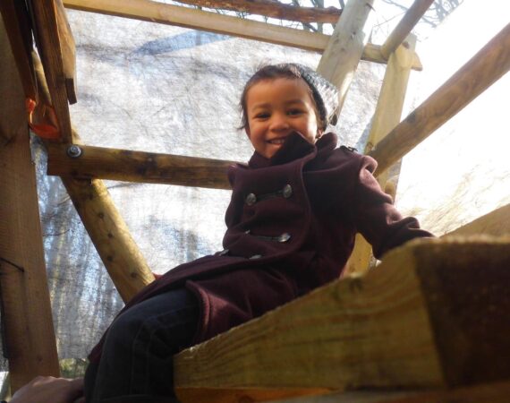 Enfant qui sourit dans une cabane en bois