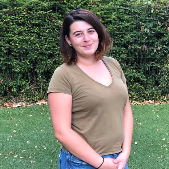 Une jeune femme aux mains croisées dans un jardin