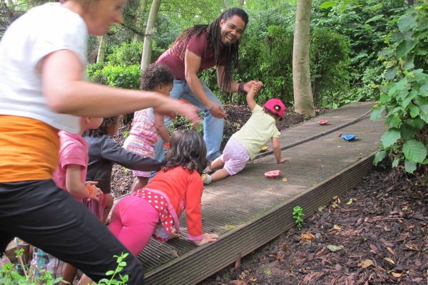 Cinq enfants accompagnés de deux éducateurs faisant de l'escalade dans les bois