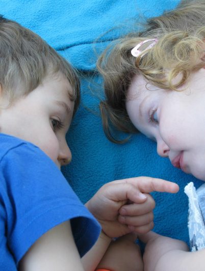Deux enfants couchés sur une couverture bleue