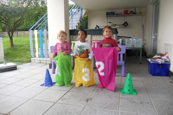 Trois enfants s'apprêtent à faire une course en sac