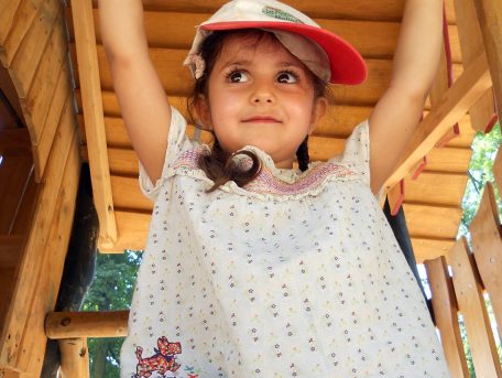Une petite fille avec une casquette dans une plaine de jeux